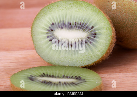 freshly cut ripe kiwifruit sitting on a wooden chopping board Stock Photo