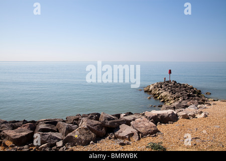 one man fishing off Rock stone groynes sea defences at Barton on Sea Stock Photo