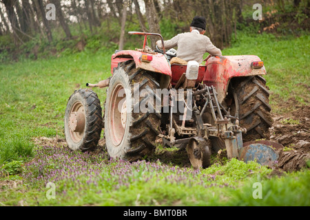 Senior farmer using an old tractor to plow his land Stock Photo