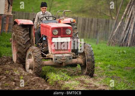 Senior farmer using an old tractor to plow his land Stock Photo