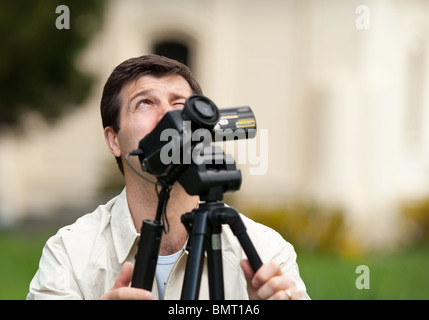 Young man using camcorder on a tripod outdoors in a forest Stock Photo