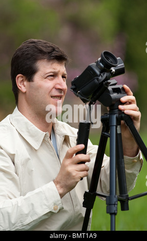 Young man using camcorder on a tripod outdoors in a forest Stock Photo