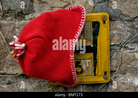 Lost red hat placed on a hydrant sign Stock Photo