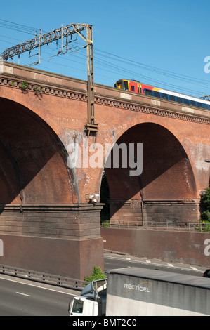 Train travels across Stockport viaduct, with the M60 motorway below. Stock Photo