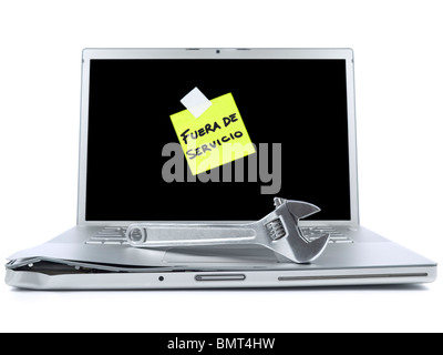 Damaged laptop with a post-it in spanish meaning Out of Service and a spanner over it. Isolated on white. Stock Photo