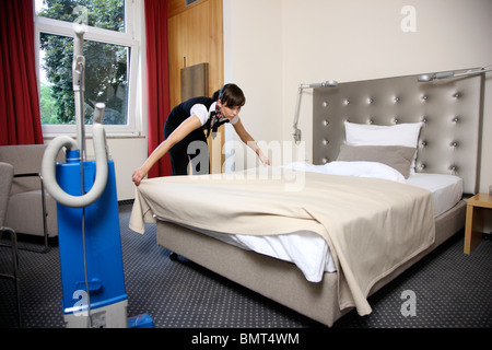 Hotel, room service, house keeping at work in a hotel room. Cleaning up, making the beds. Stock Photo