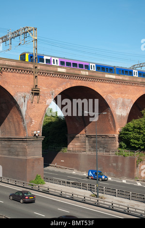 Train travels across Stockport viaduct, with the M60 motorway below. Stock Photo