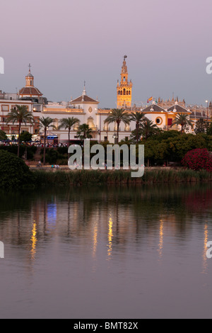 The La Giralda tower and bullring at dusk seen from the Triana bank of the Guadalquivir river in Seville Andalucia Spain Europe Stock Photo
