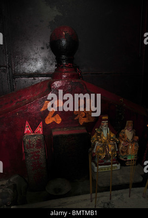 Two white bearded taoist figurines standing in front of a red altar in a dark shrine room. Pak Sing Ancestral Hall, Hong Kong Stock Photo