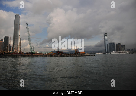 Dark cloud view of land reclamation, extending into Victoria Harbour, between the skyscrapers of Central and Kowloon, Hong Kong Stock Photo