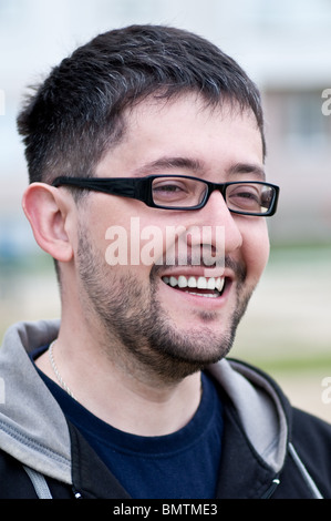 Portrait of a young male caucasian student with beard and glasses smiling Stock Photo