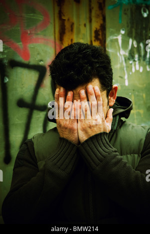 Man hiding face in hands outdoors Berlin Germany
