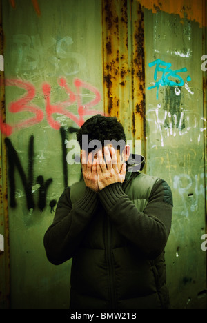Man hiding face in hands outdoors Berlin Germany