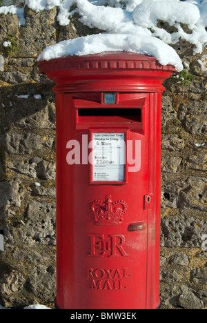 A red "Royal Mail" pillar box with snow on the top photographed in Watchfield, Oxfordshire, England, UK Stock Photo