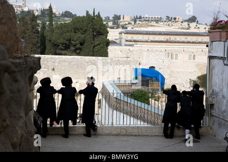 Orthodox Hasidic Jews in old Jerusalem looking over fence towards Western wall Stock Photo