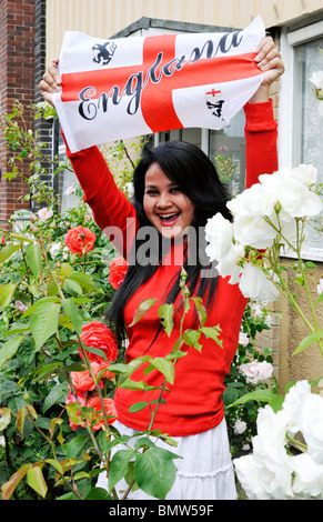 young asian woman waving england flag and dressed in red and white to show her support for england during the football world cup Stock Photo