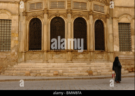 muslim lady walking past one of the many mosques in islamic cairo, early morning scene , islamic cairo , cairo , egypt Stock Photo