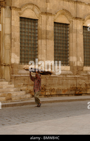 bread delivery man walking past one of the many mosques in islamic cairo, early morning scene , islamic cairo , cairo , egypt Stock Photo