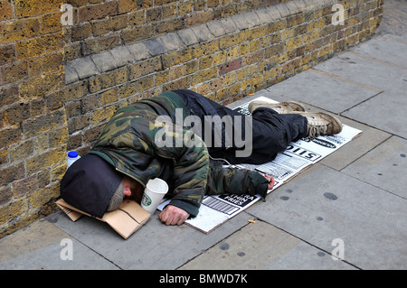 Homeless Man sleeping on pavement in London Stock Photo