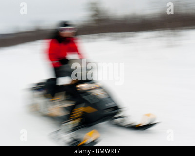 A young man drives a snow mobile through the snow at Kiruna, Lapland, Northern Sweden. Stock Photo