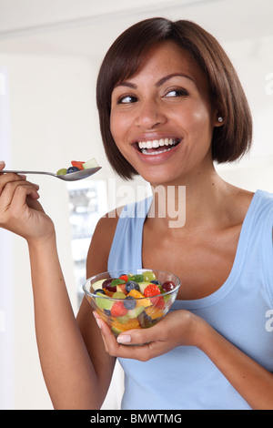 WOMAN EATING FRESH FRUIT SALAD Stock Photo