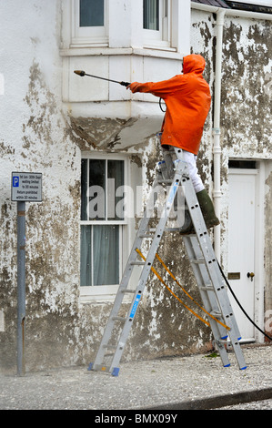 Workman pressure-washing house front. Shore Street. Ullapool, Loch Broom, Ross and Cromarty, Scotland, United Kingdom, Europe. Stock Photo