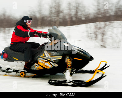 A young man drives a snow mobile through the snow at Kiruna, Lapland, Northern Sweden. Stock Photo
