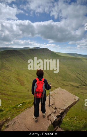 A walker looks over to Pen y Fan & Cribyn  from a ledge on Fan y Big in the Brecon Beacons South Wales Stock Photo