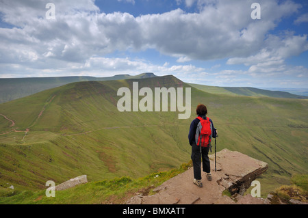 A walker looks over to Pen y Fan &  Cribyn from a ledge on Fan y Big in the Brecon Beacons South Wales Stock Photo