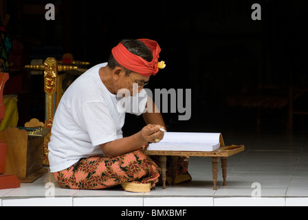 On the Hindu holiday of Saraswati, celebrating the goddess of books and knowledge, a Bali man in formal wear reads a book. Stock Photo