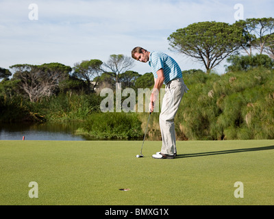Man playing golf, on putting green Stock Photo