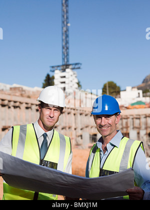 Mature men with blueprint on construction site Stock Photo