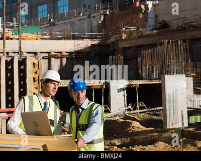 Mature men using laptop on construction site Stock Photo