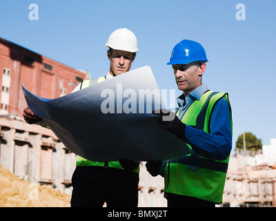 Mature men inspecting blueprints on construction site Stock Photo