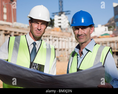 Mature men with blueprint on construction site Stock Photo