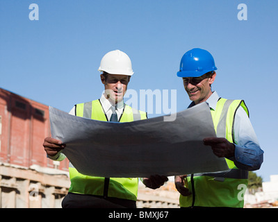 Mature men inspecting blueprints on construction site Stock Photo