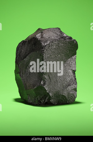 A large piece of black bituminous coal on a bright green background Stock Photo