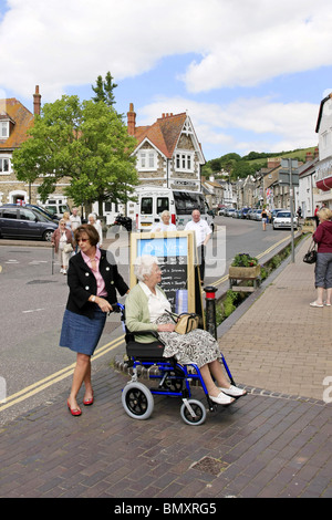 wheelchair bound woman and her cacer on a day out to Beer in Devon England Stock Photo