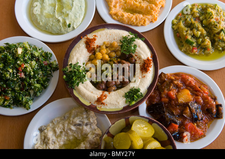 Plate of Hummus with Ful or Foul brown fava beans with all sort of Mediterranean typical mezze salads served in a restaurant Israel Stock Photo