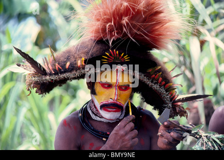 A Huli Wigman paints his face in bright colors for a traditional sing-sing ceremony at Tari in the Southern Highlands of Papua New Guinea (PNG). Stock Photo