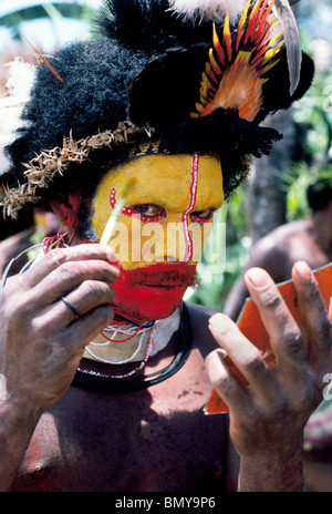 A Huli Wigman paints his face in bright colors for a traditional sing-sing ceremony at Tari in the Southern Highlands of Papua New Guinea (PNG). Stock Photo