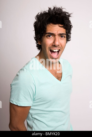 Portrait of dark haired young man shouting - studio shot Stock Photo