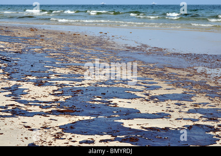 Oil spill on beach with oil skimmers in background. Stock Photo