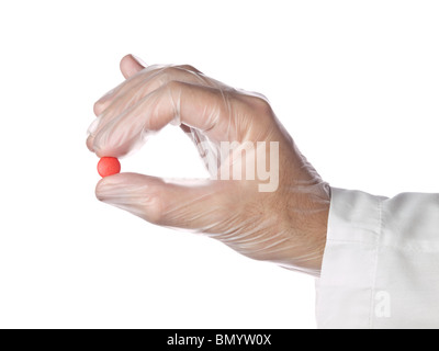 A doctor holds a red pill with his latex gloves on. Isolated on white. Stock Photo