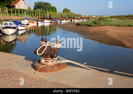 Bollard with ropes and moored boats by the quay at Blakeney, Norfolk, England, United Kingdom. Stock Photo