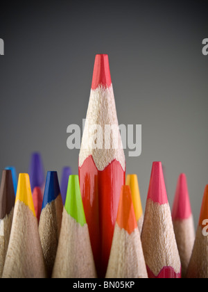 Red pencil coming out among many colored pencils. Stock Photo