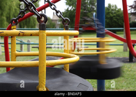 Empty swings in a child's playground, movement on one swing Stock Photo
