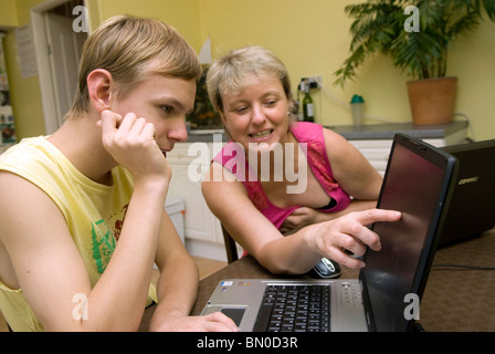 Young boy who has mild autism at home with his mum working on laptop, Sutton, UK. Stock Photo