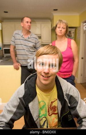 Young boy who has mild autism at home with his mum and dad in background, Sutton, UK. MR Stock Photo