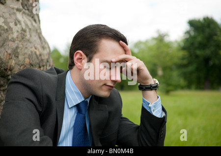 Stressed businessman sitting in park Stock Photo